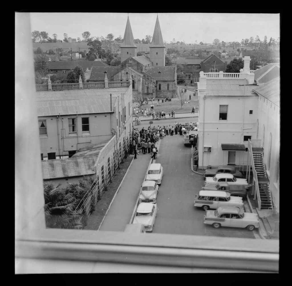 A view of Church Street Parramatta, circa 1959. This image may have been taken from inside the Administrative Building, and shows a crowd queuing along the street. Also featured are the Town Hall and St. John's Anglican Cathedral. City of Parramatta Archives: PRS111/1030