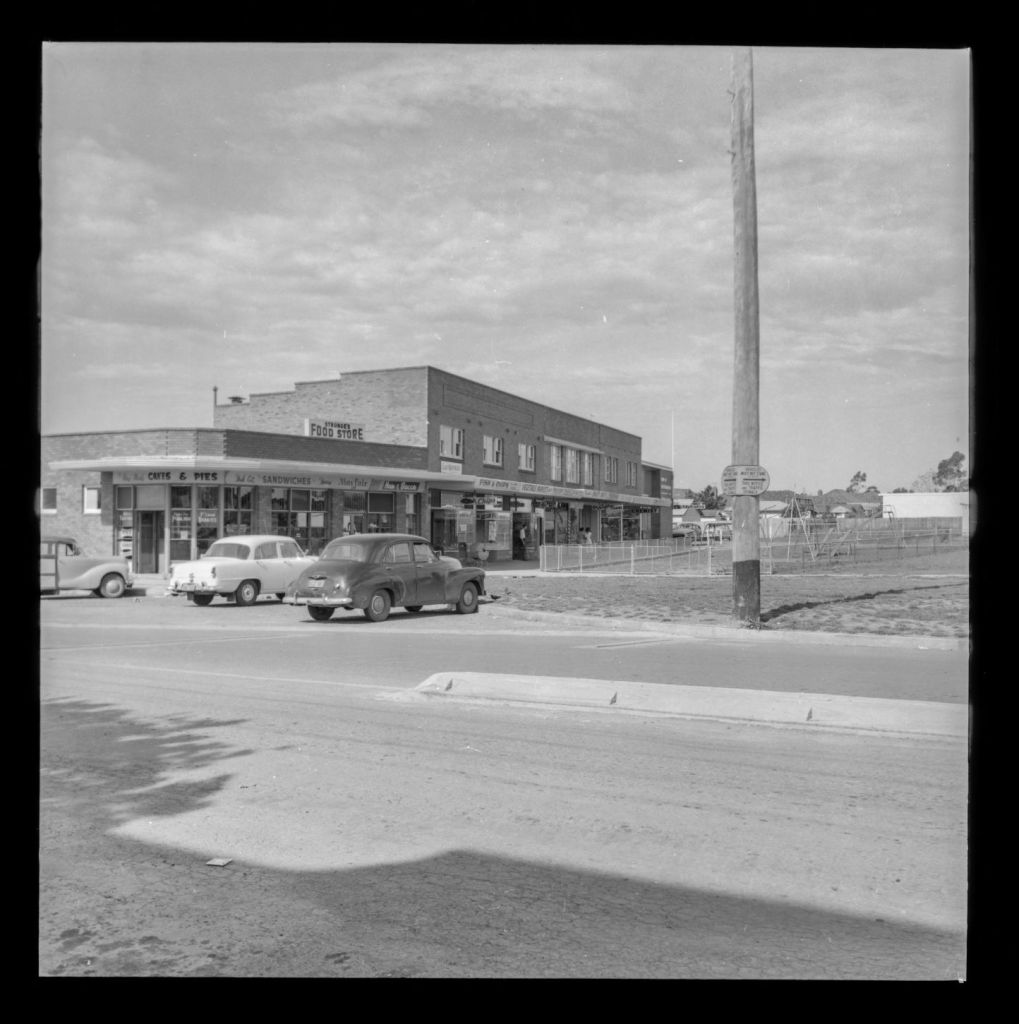The corner of Victoria and Park Road, Rydalmere circa 1959. Featured in this image are shops including Strange's Food Store, Swift Dry Cleaning, a fish and chip shop, milk bar and a chemist. A playground can be seen at the front of the image in what is now John Carver Reserve. City of Parramatta Archives: PRS111/1027